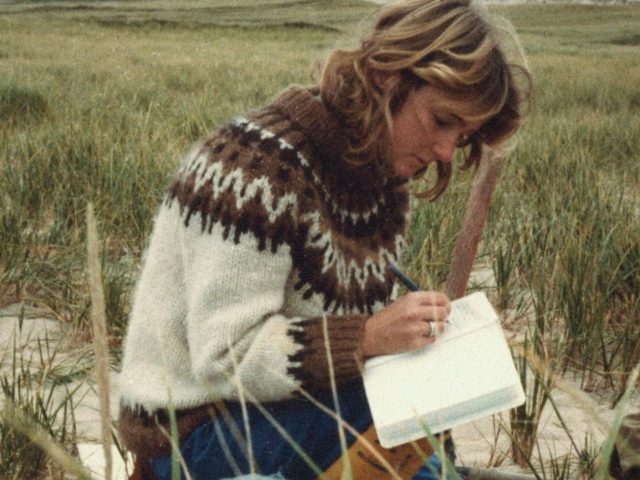 woman sat in field writing in book