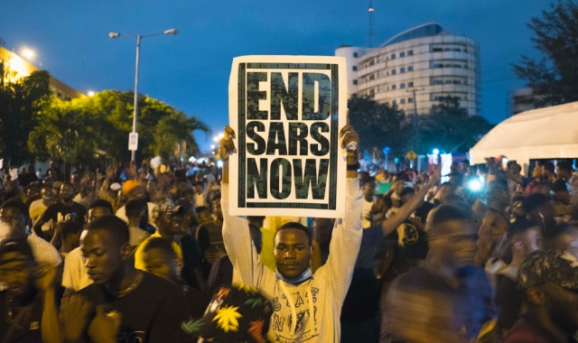 Man in protest holding up a placard that says End SARS now